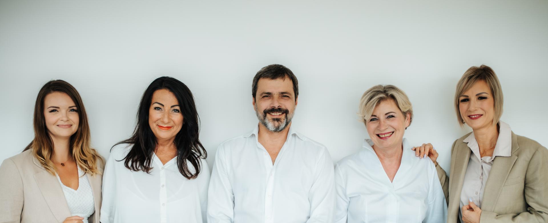 BEAUTY SOLUTIONS Team | Geschäftsführung & Außendienst | © BEAUTY SOLUTIONS | Martin Hofmann Fotografie Ein Teil vom BEAUTY SOLUTIONS Außendienst Team mit Geschäftsführer Robert Juričev. Fünf lächelnden Personen in Business-Kleidung vor einem weißen Hintergrund. Vier Frauen in modernen Blusen und Blazer stehen neben einem Mann im weißen Hemd. Die entspannte Haltung und der neutrale Hintergrund vermitteln Professionalität und Teamgeist.