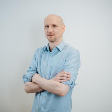 BEAUTY SOLUTIONS Team | System Administrator | Andreas Resi | © BEAUTY SOLUTIONS | Martin Hofmann Fotografie Ein Mann in einem hellblauen Hemd steht mit verschränkten Armen vor einem neutralen Hintergrund. Der entspannte und selbstbewusste Ausdruck verleiht dem Porträt eine professionelle Ausstrahlung.