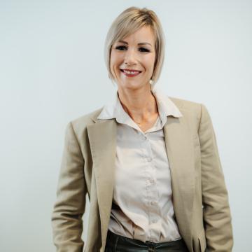 BEAUTY SOLUTIONS Team | Sales Area Manager | Manuela Dobias | © BEAUTY SOLUTIONS | Martin Hofmann Fotografie Ein stilvolles Porträt einer lächelnden Frau in einem beigefarbenen Blazer und einer weißen Bluse. Der neutrale Hintergrund lenkt die Aufmerksamkeit auf ihre freundliche Ausstrahlung, ideal für berufliche Präsentationen und Profile.