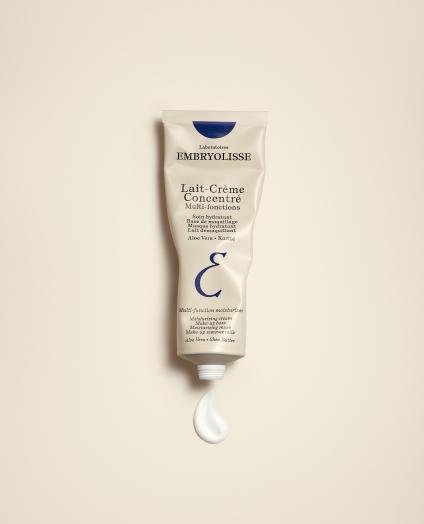 Eine Tube Embryolisse Lait-Crème Concentré, die auf einer hellen Oberfläche liegt. Aus der Tube fließt eine kleine Menge der reichhaltigen, feuchtigkeitsspendenden Creme. Ein essenzielles Produkt für hydratisierte, weiche Haut.