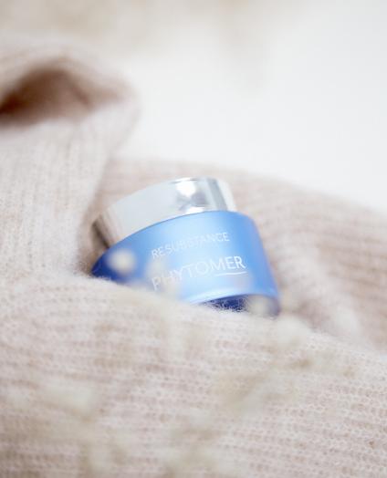 BEAUTY SOLUTIONS Kosmetikmarken | PHYTOMER Resubstance Creme | © PHYTOMER Codif International Ein eleganter blauer Tiegel mit reichhaltiger Creme, eingebettet in einem weichen beigen Stoff. Das Bild vermittelt ein Gefühl von Luxus und Komfort, ideal für Hautpflegeprodukte. Die sanfte Beleuchtung hebt die hochwertige Verpackung hervor.